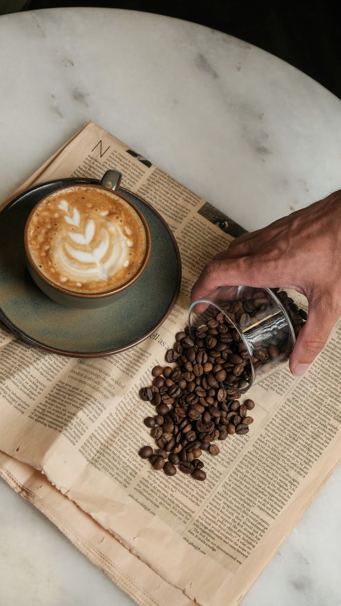 services-02 A cappuccino in a ceramic cup and coffee beans on a newspaper, creating a cozy coffee break scene.