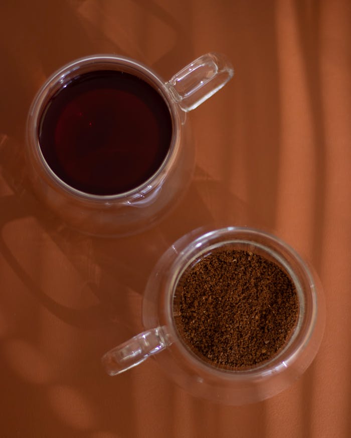 services-03 Top view of ground coffee and brewed drink in glass cups on an orange surface.