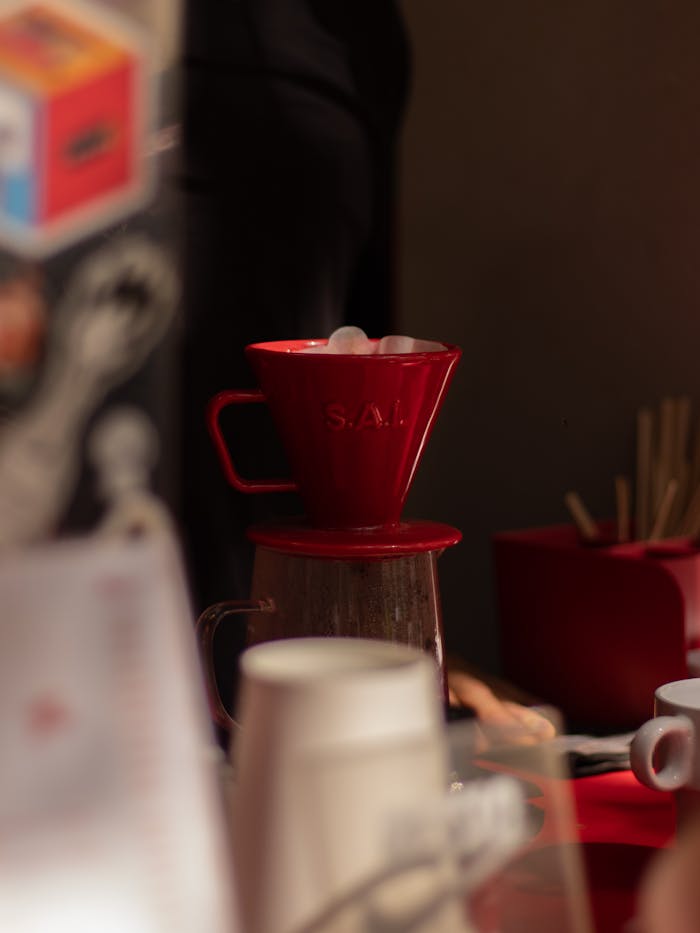 services-01 A red coffee dripper in a cozy cafe setup, capturing a warm and inviting atmosphere.
